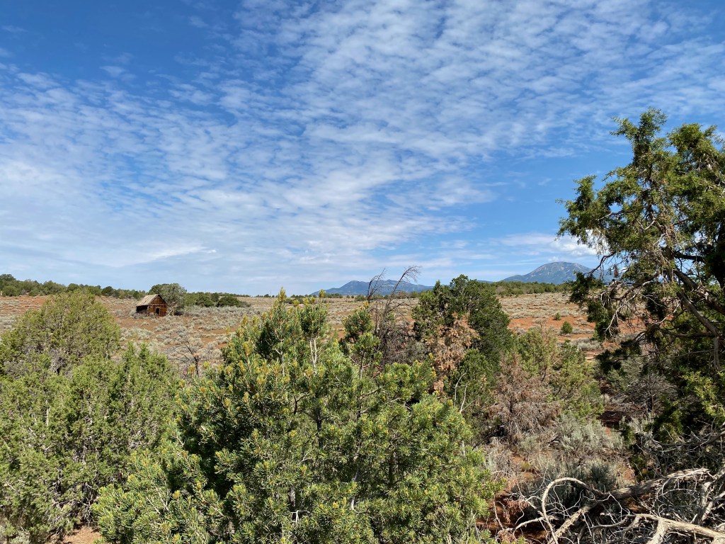 cabin in the distance with mountains on the horizon